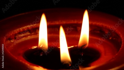 Candle with three candlewicks in dark interior