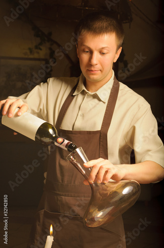 A sommelier pouring red wine into decanter