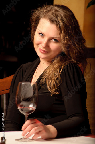 Beautiful young woman sitting with a wineglass in the restaurant