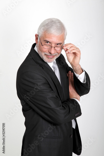 Senior businessman with eyeglasses standing on white background © goodluz