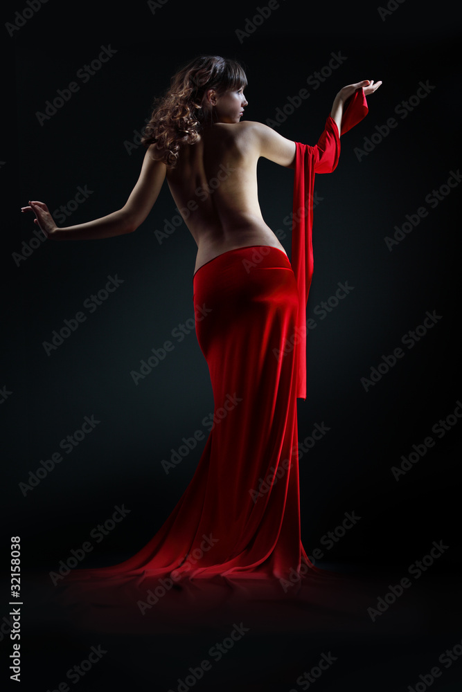 The girl in a red dress against a dark background The girl in a red dress against a dark background