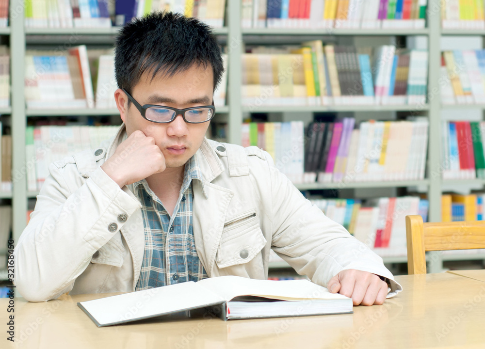 Handsome man sitting and reading in library Handsome man sitting and reading in library