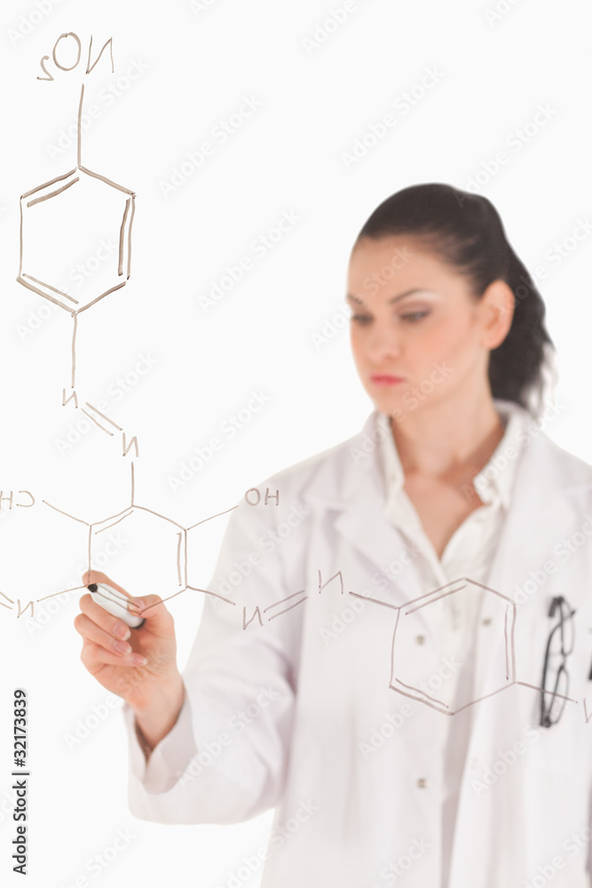Dark-haired scientist writing a formula on a white board Dark-haired scientist writing a formula on a white board