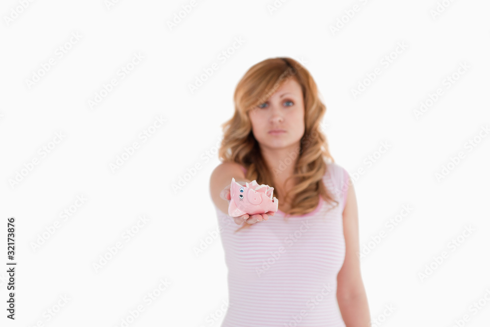 Attractive blond-haired woman showing her broken piggybank Attractive blond-haired woman showing her broken piggybank