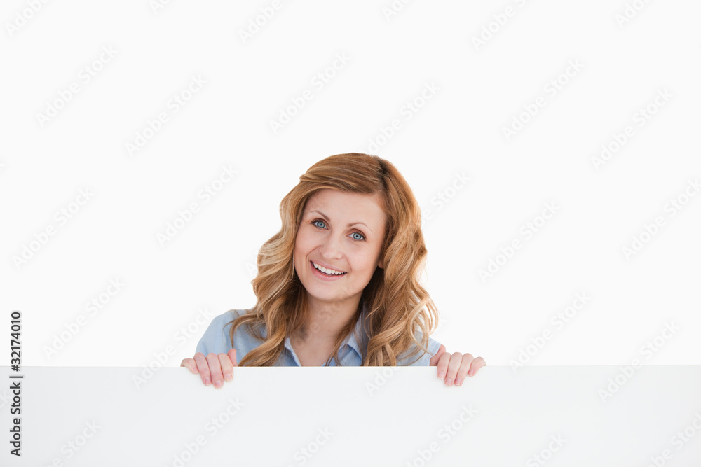 Lovely blond-haired woman standing behind an empty white board Lovely blond-haired woman standing behind an empty white board