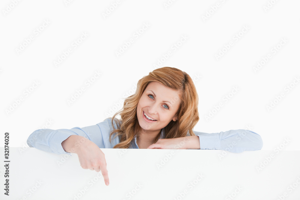 Cute blond-haired woman standing behind an empty white board Cute blond-haired woman standing behind an empty white board