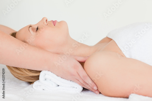 Lovely blond-haired woman lying down while receiving a spa treat