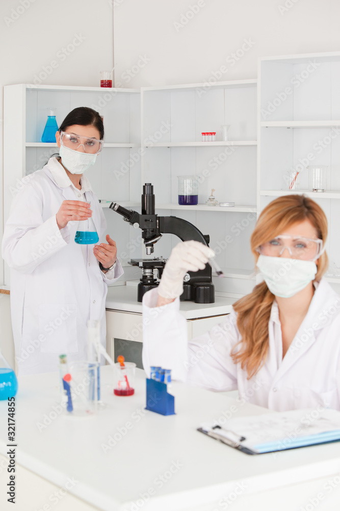 Blond-haired and dark-haired scientists conducting an experiment Blond-haired and dark-haired scientists conducting an experiment