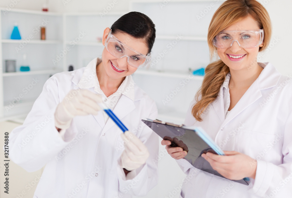 Two scientists looking at the camera while holding a test tube a Two scientists looking at the camera while holding a test tube a