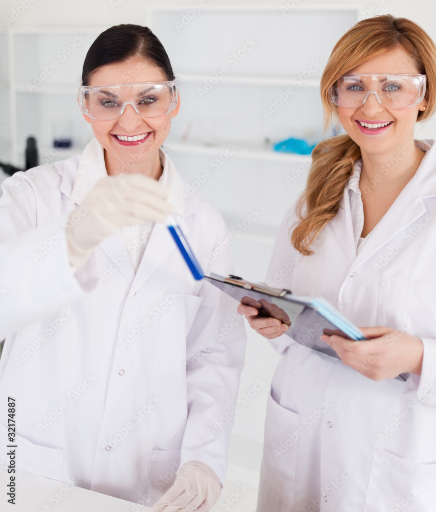 Two scientists looking at the camera while holding a test tube a Two scientists looking at the camera while holding a test tube a