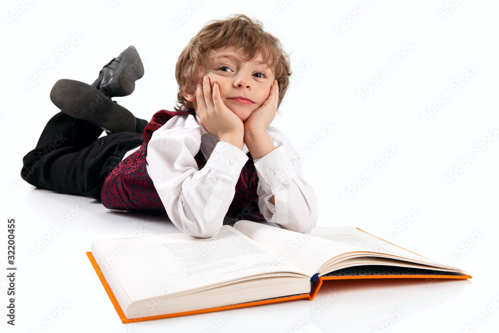 Cute little boy daydreaming while reading book Cute little boy daydreaming while reading book