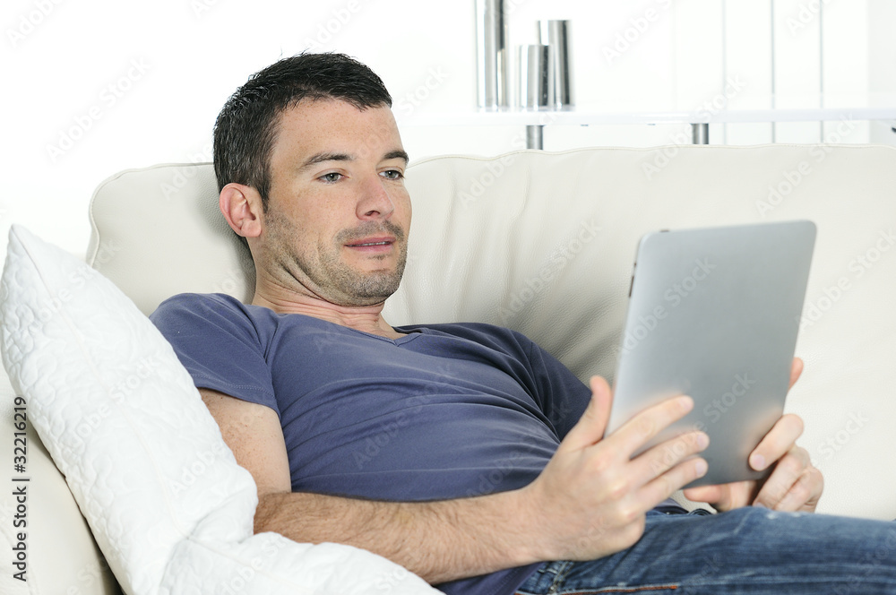 attractive relaxed and positive man is surfing on his tablet