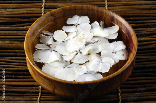 bowl of water white hydrangea petals on bamboo mat