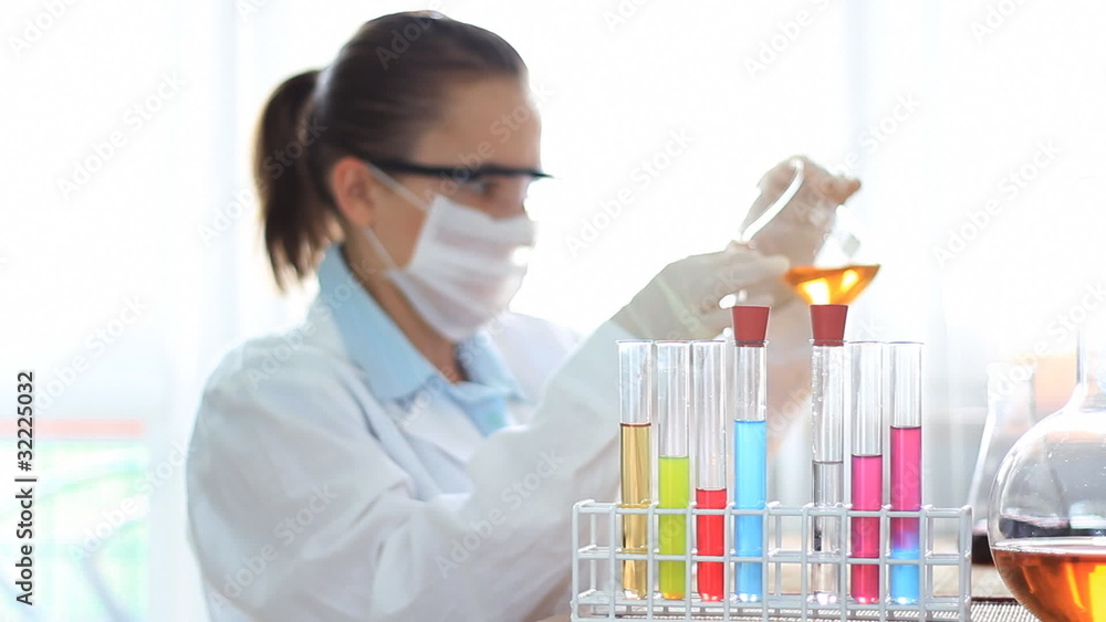 Female scientist looking pouring chemicals into test tube Female scientist looking pouring chemicals into test tube
