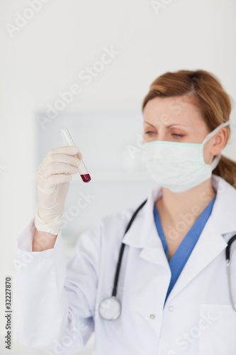 Blond-haired scientist with a mask looking at a test tube