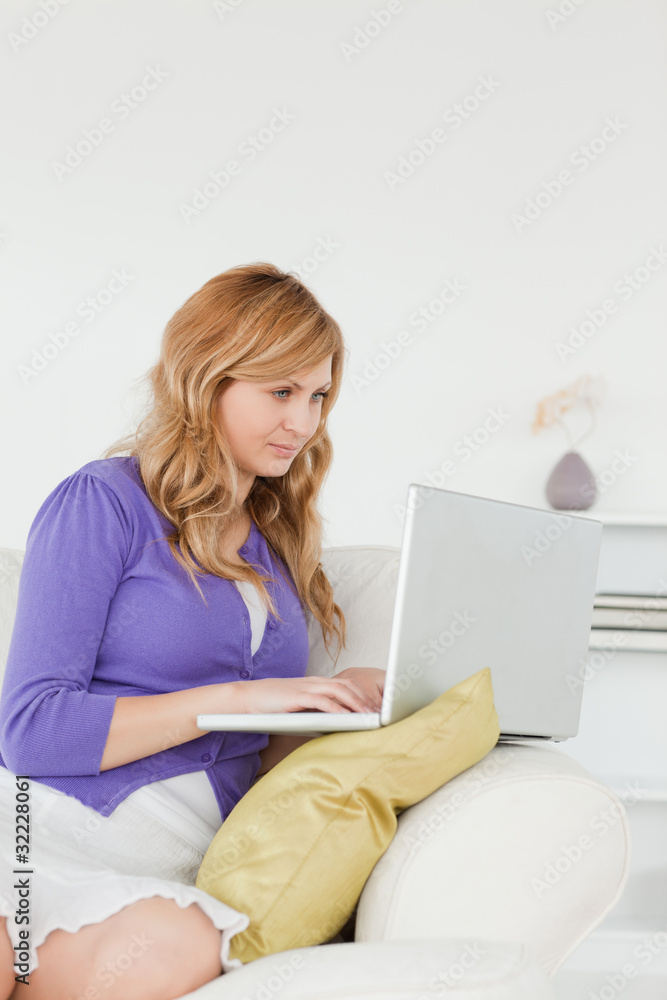 Prettyl red-haired woman sitting on the sofa and using a laptop Prettyl red-haired woman sitting on the sofa and using a laptop