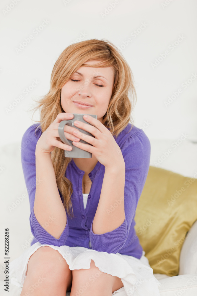 Beautiful red-haired woman holding and smelling a cup of coffee Beautiful red-haired woman holding and smelling a cup of coffee