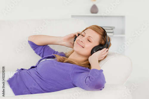 Good looking red-haired woman listening to music and enjoying th