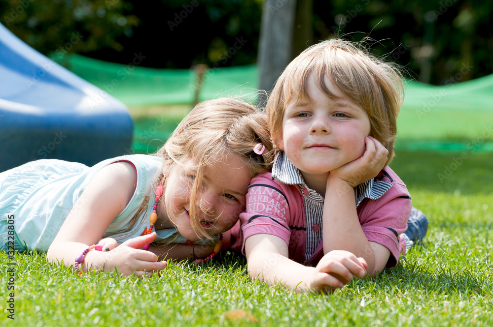 Zwei Kinder liegen auf dem Rasen Stock Photo | Adobe Stock