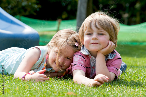 Zwei Kinder liegen auf dem Rasen