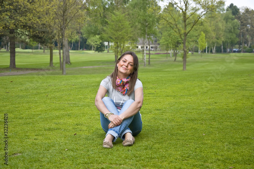 Beautiful attractive woman sitting on a green grass