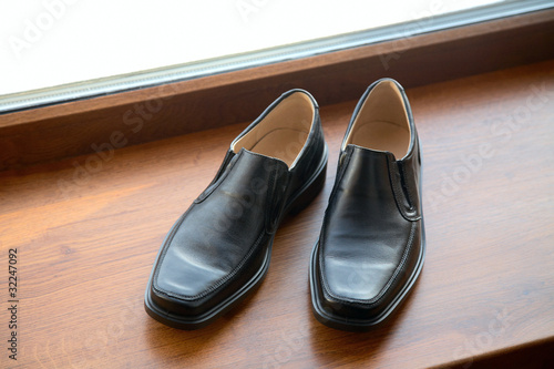 man's shoes stand on a window sill