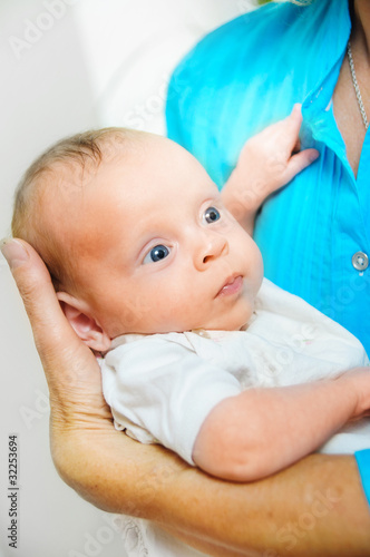 Happy cute infant lying on his grandmother hands