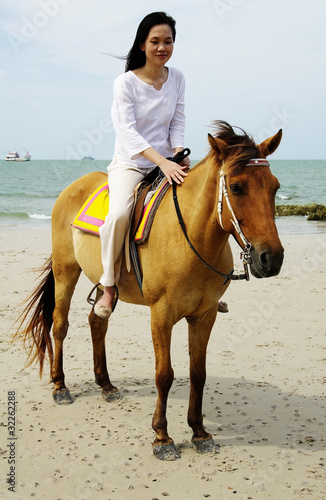 young woman riding a horse on the beach