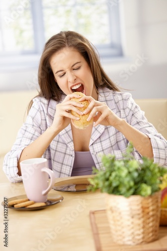 Hungry woman biting into sandwich