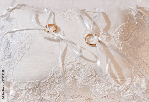 Gold wedding rings on a white pillow.