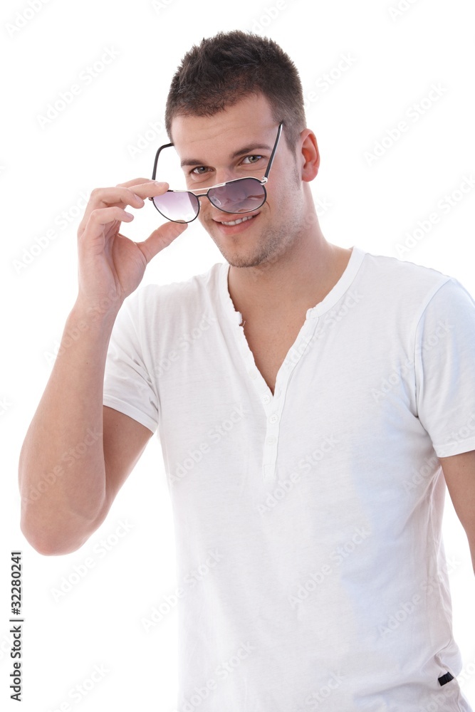 Young man putting on sunglasses smiling