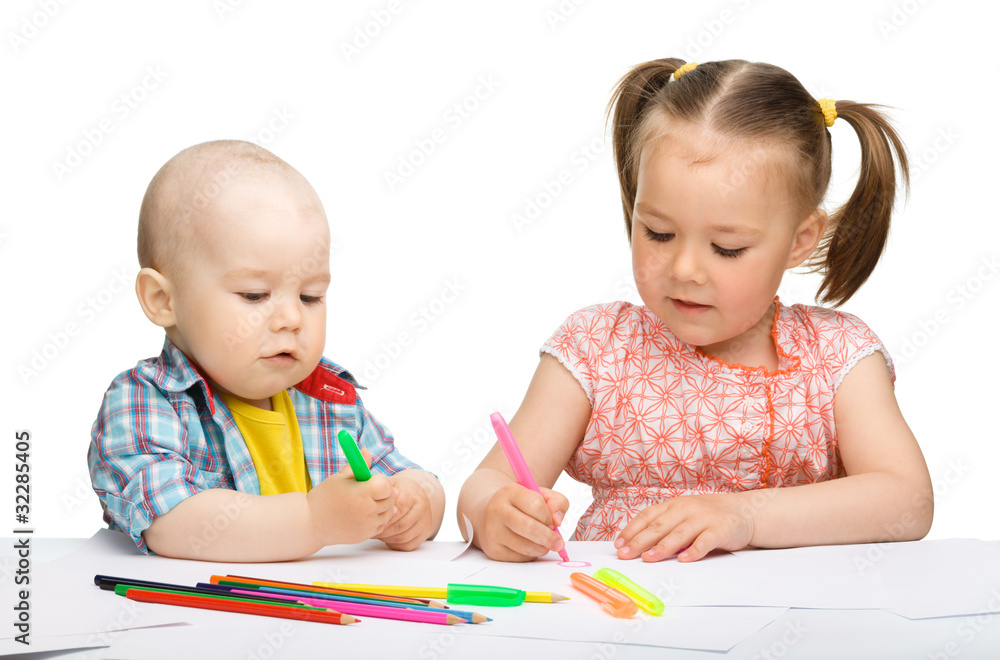 Two children are drawing on paper using markers Two children are drawing on paper using markers