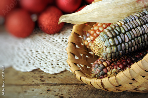 Ear of Indian corn in basket with Christmas balls in background