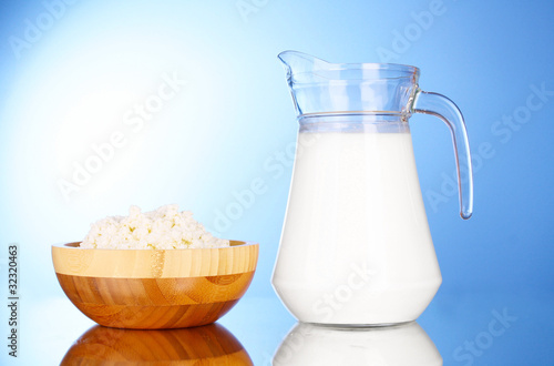 Pitcher with milk and cottage cheese on blue background with ref