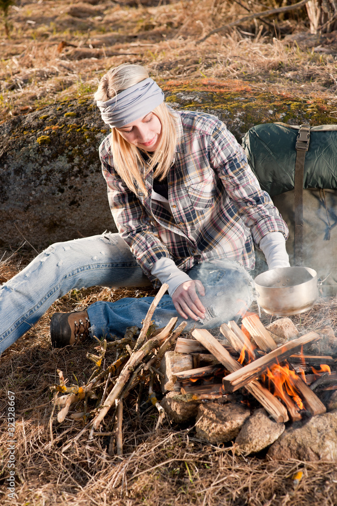 Hiking woman with backpack cook by campfire Hiking woman with backpack cook by campfire