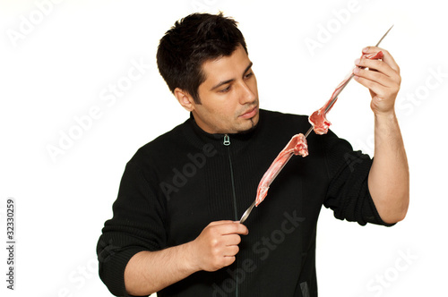 Young man putting lamb chops on a skewer for bbq