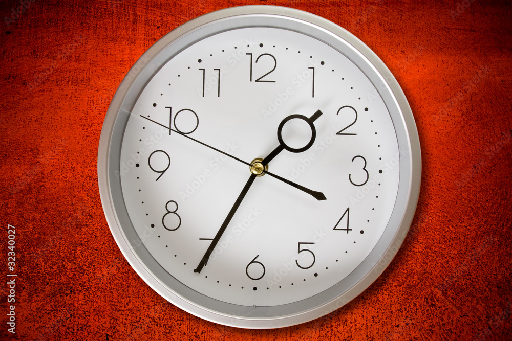 silver clock on a dirty red wall background silver clock on a dirty red wall background