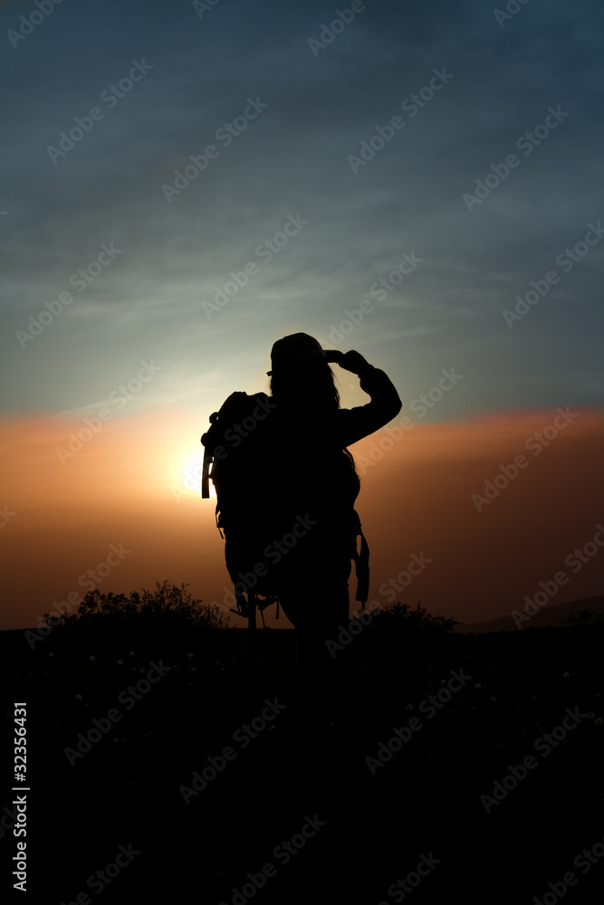 girl with a backpack in the mountains at sunset