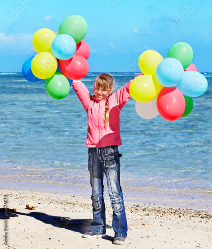 Child playing with balloons at the beach