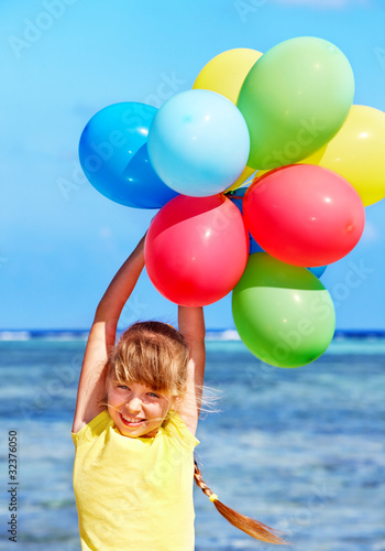 Child playing with balloons at the beach