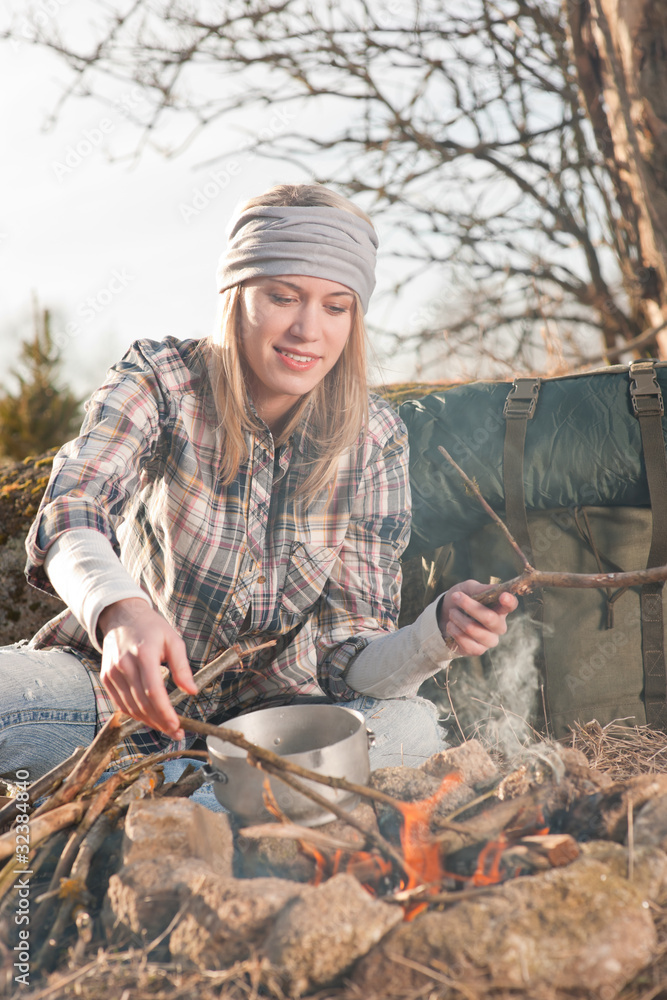 Hiking woman with backpack cook by campfire Hiking woman with backpack cook by campfire