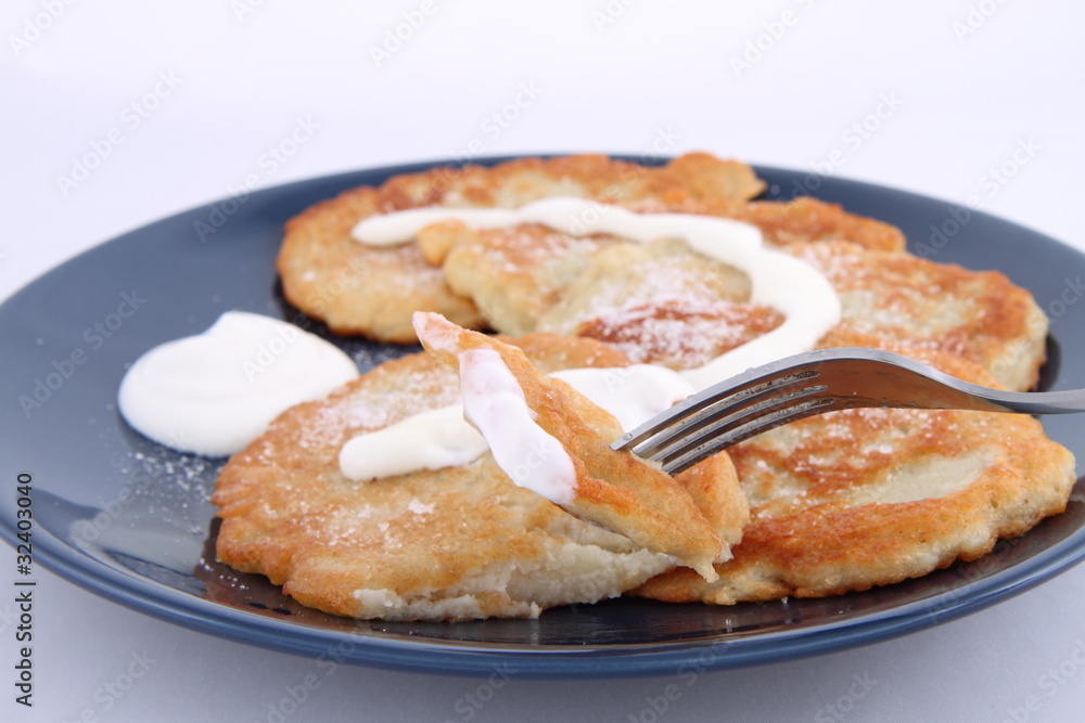 Potato pan cakes with cream and sugar being eaten with a fork Potato pan cakes with cream and sugar being eaten with a fork
