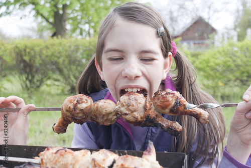 Obraz na płótnie Teen girl bites grilled meat outdoors w salonie