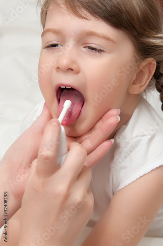 doctor splashing aerosol a throat to girl