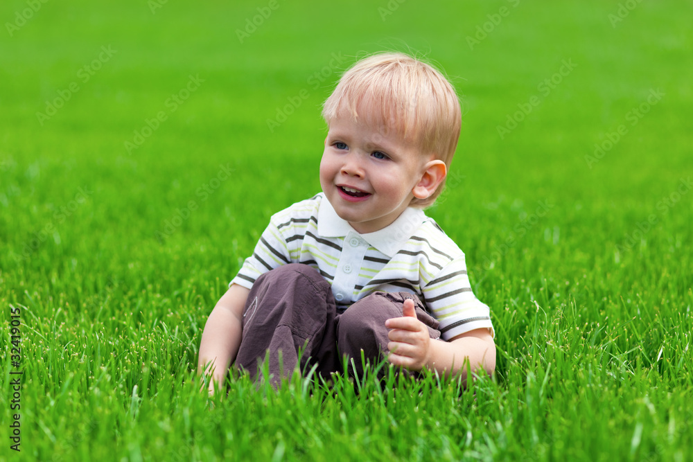 Smiling little boy sitting in fresh grass Smiling little boy sitting in fresh grass