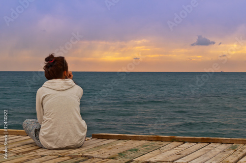 the girl looks at the sea sunset