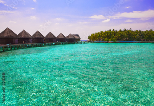 Maldives. Island in ocean and overwater villas .