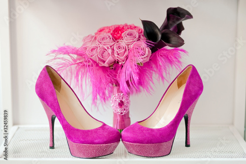 Bridal bouquet of roses and pink shoes are on a shelf