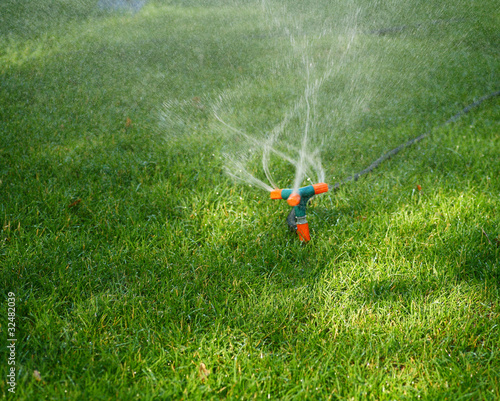 Sprinkler Spraying Water On Grass photo