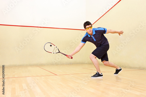 Squash player hiting a ball in a squash court photo